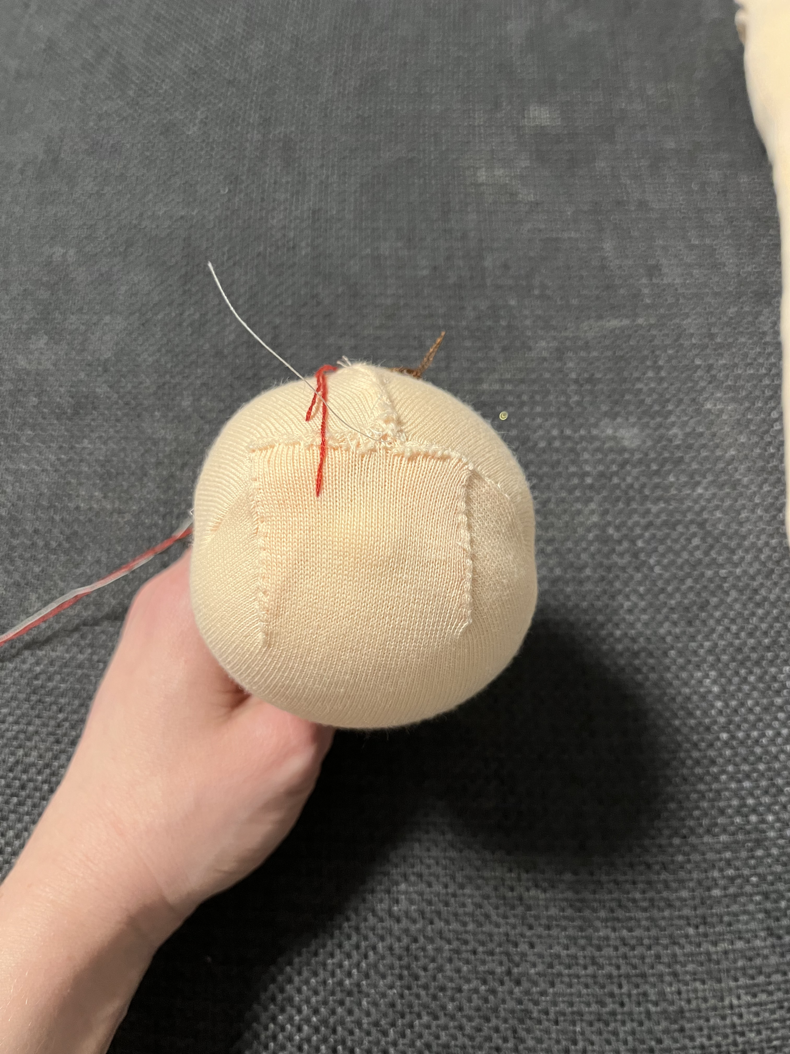 Person hand-stitching a soft doll