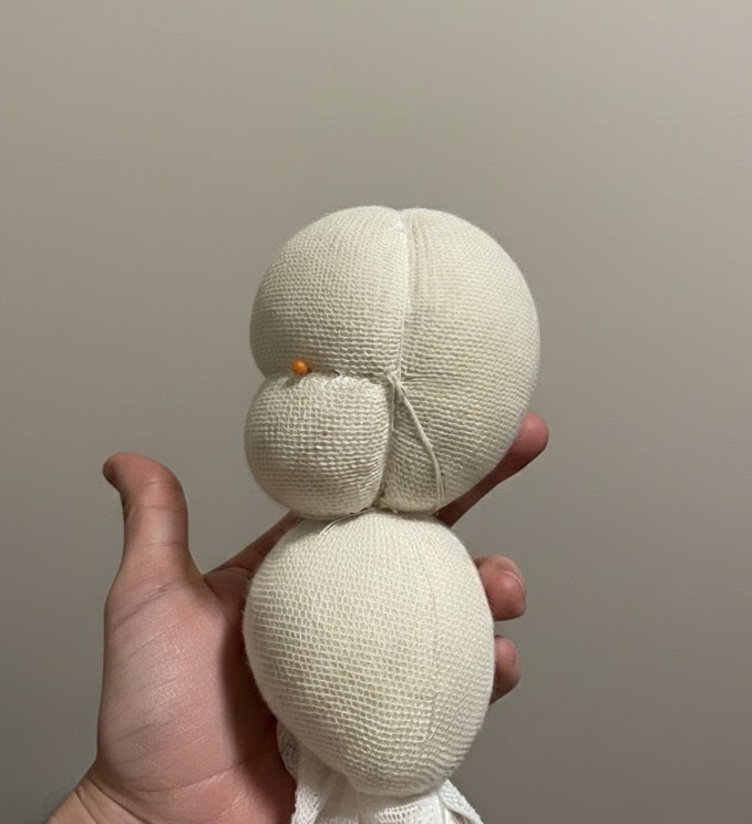 Person hand-stitching a soft doll