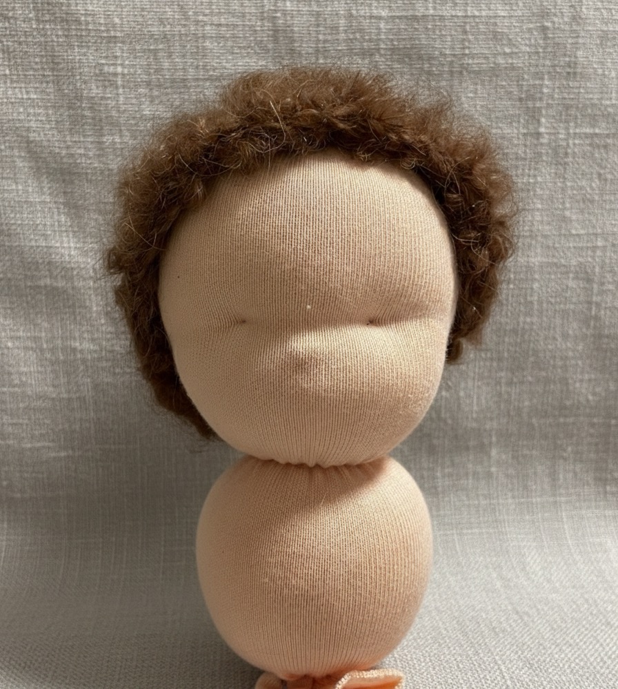 Person hand-stitching a soft doll