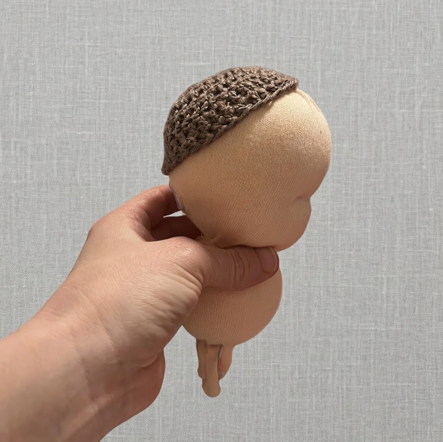 Person hand-stitching a soft doll